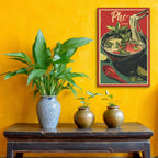 Three potted plants on a wooden table against a yellow wall with a Pho poster.