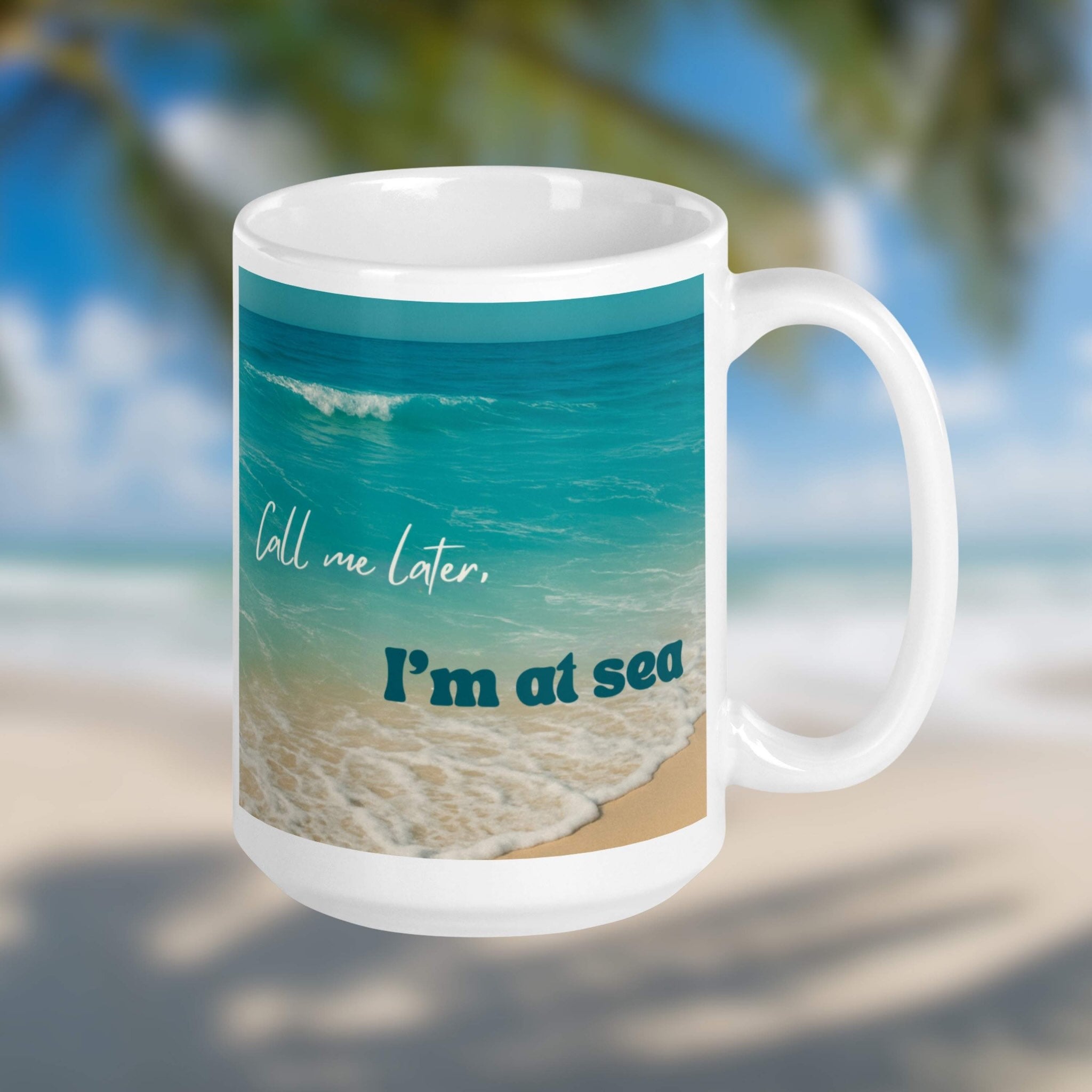 15 oz mug with beach design and text 'Call me later, I'm at sea' against a blurred beach background
