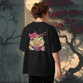 Man wearing a black t-shirt with a colorful graphic of japanese ramen soup with pun 'Send Noods' on the back, standing in front of a stylized tree and wall, japanese style.