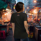 Woman in a black t-shirt with a logo standing in a bustling asian night market.
