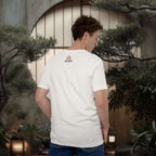 Person wearing a white t-shirt with a logo in a japanese outdoor setting with plants and lanterns.