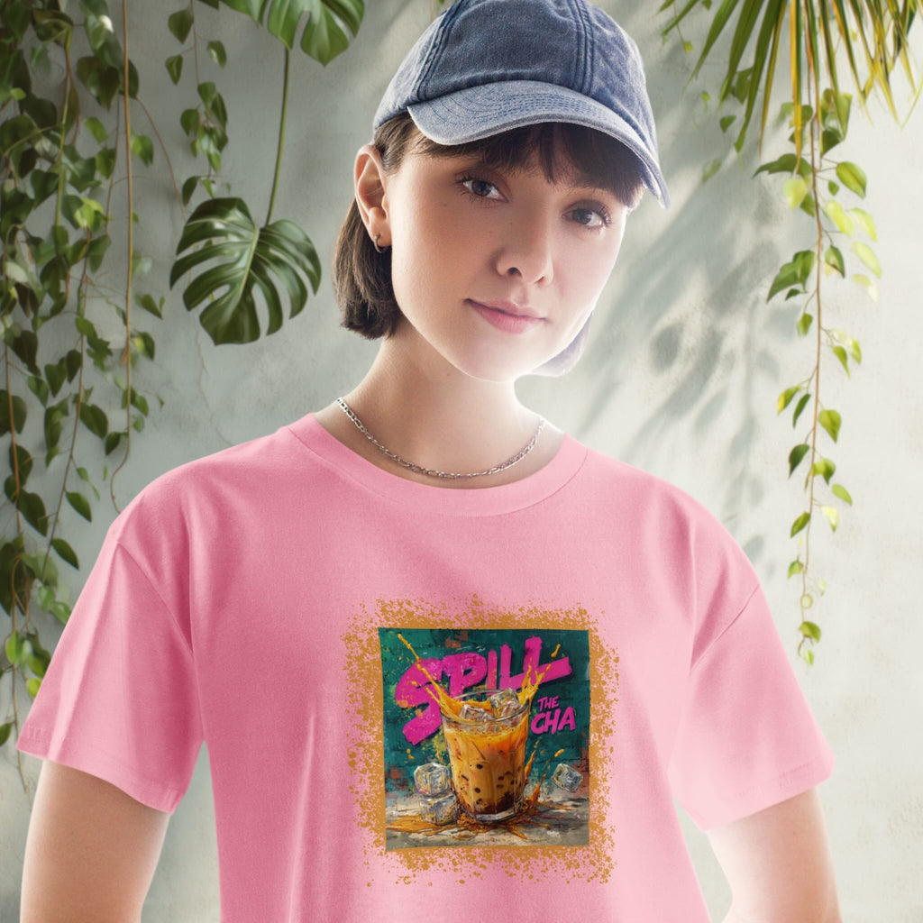 Person wearing a pink crop top with a colorful graphic design in front of green plants.