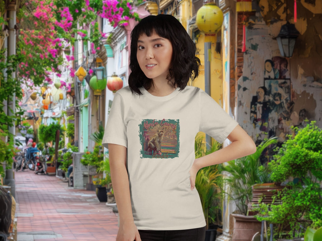 Woman wearing a t-shirt with a colorful graphic design of Batu Caves Bandit monkey front print in an outdoor setting with plants and decorations.