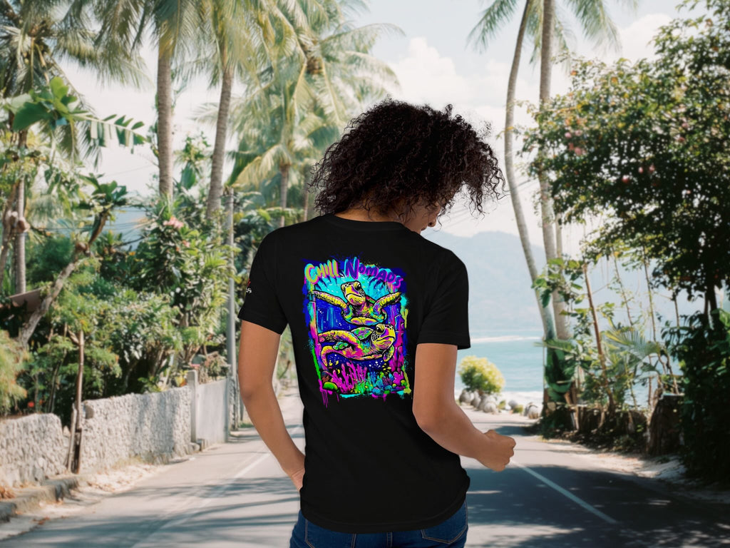 Person wearing a black t-shirt with a colorful graphic design in a tropical setting