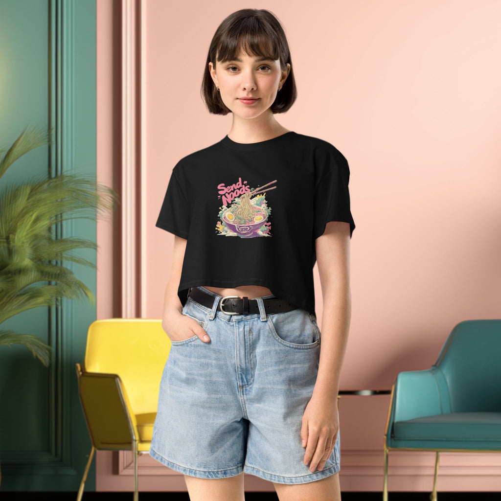 Person wearing a black crop top with colorful graphic design  of japanese ramen and denim shorts in a modern interior setting.