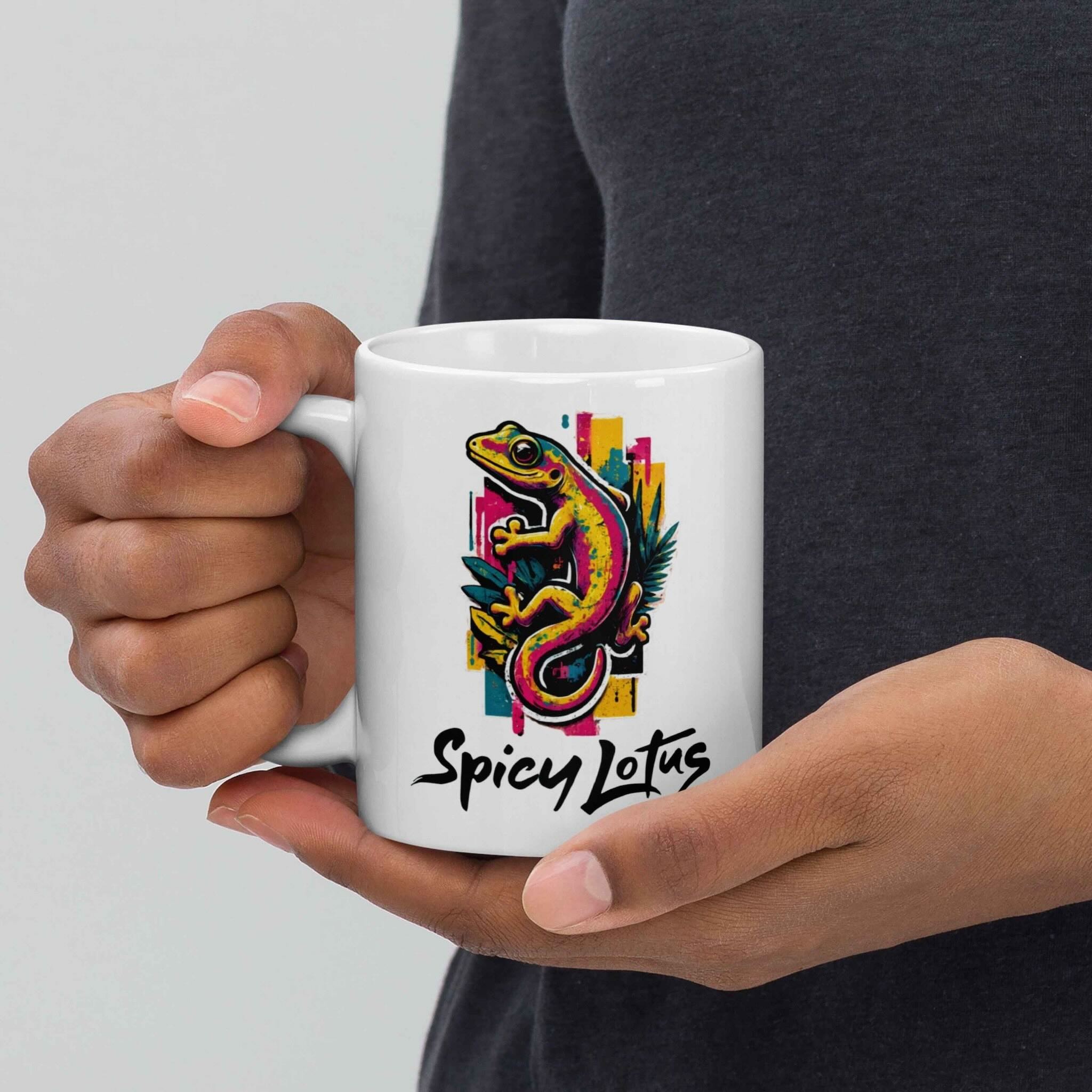 Person holding a white mug with a colorful gecko design and 'Spicy Lotus' text.