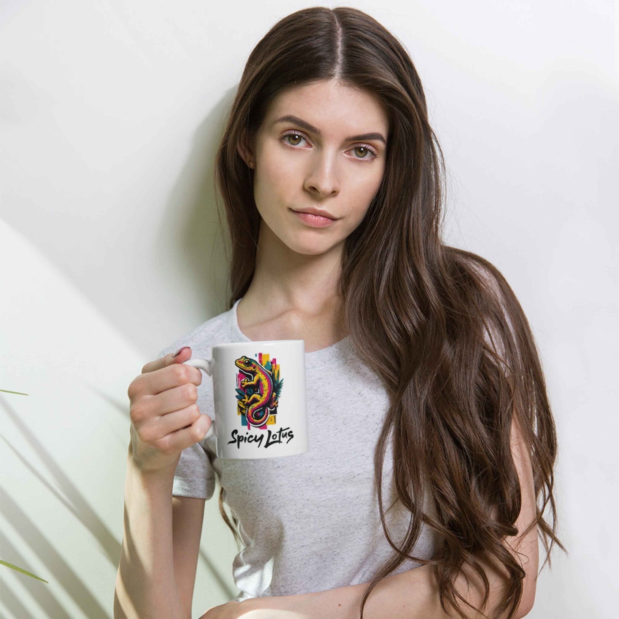 Woman holding a white mug with a gecko design against a plain background