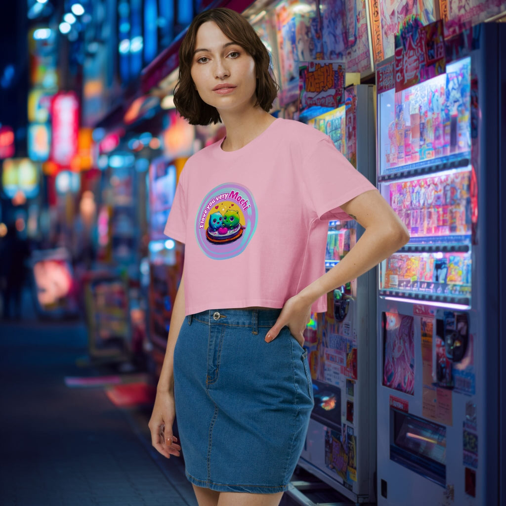 Woman wearing a pink t-shirt with a colorful graphic design of a cute mochi couple in a vibrant, neon-lit street.