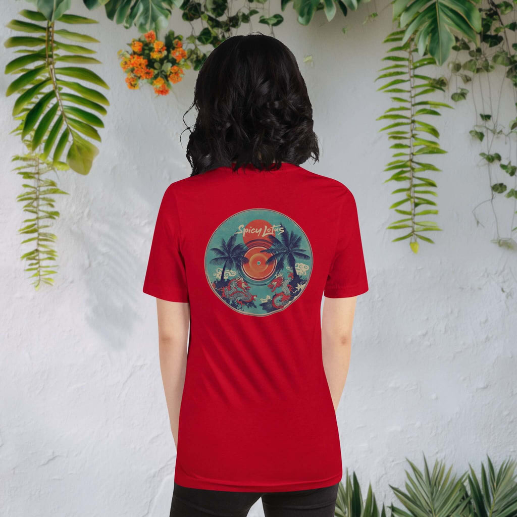 Woman wearing a red Spicy Lotus Tropical Dragons vinyl back print T-shirt in front of wall with hanging tropical plants and flowers