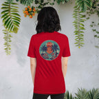 Woman wearing a red Spicy Lotus Tropical Dragons vinyl back print T-shirt in front of wall with hanging tropical plants and flowers