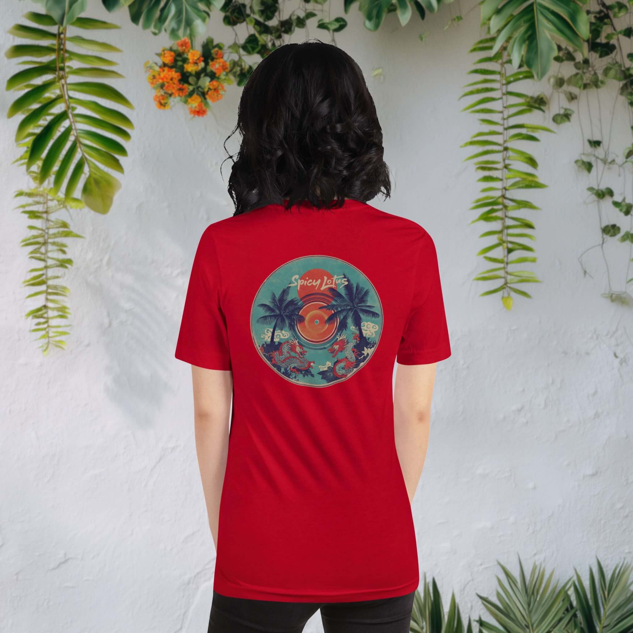 Woman wearing a red Spicy Lotus Tropical Dragons vinyl back print T-shirt in front of wall with hanging tropical plants and flowers