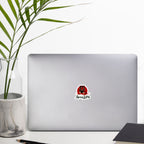 Laptop with a 'Spicy Lotus' sticker with red tiger graphic design on a white surface with a plant and notebook.