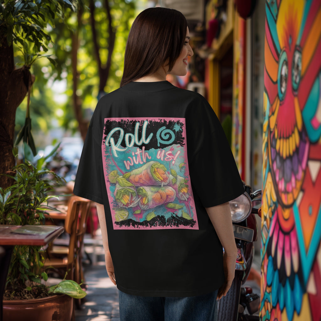 Woman wearing a black oversized  t-shirt with colorful graphic 'Roll with us' summer rolls design in an outdoor setting