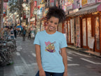 Person wearing a light blue t-shirt with a colorful graphic design of Ramen with 'Send Noods' in an urban street setting.