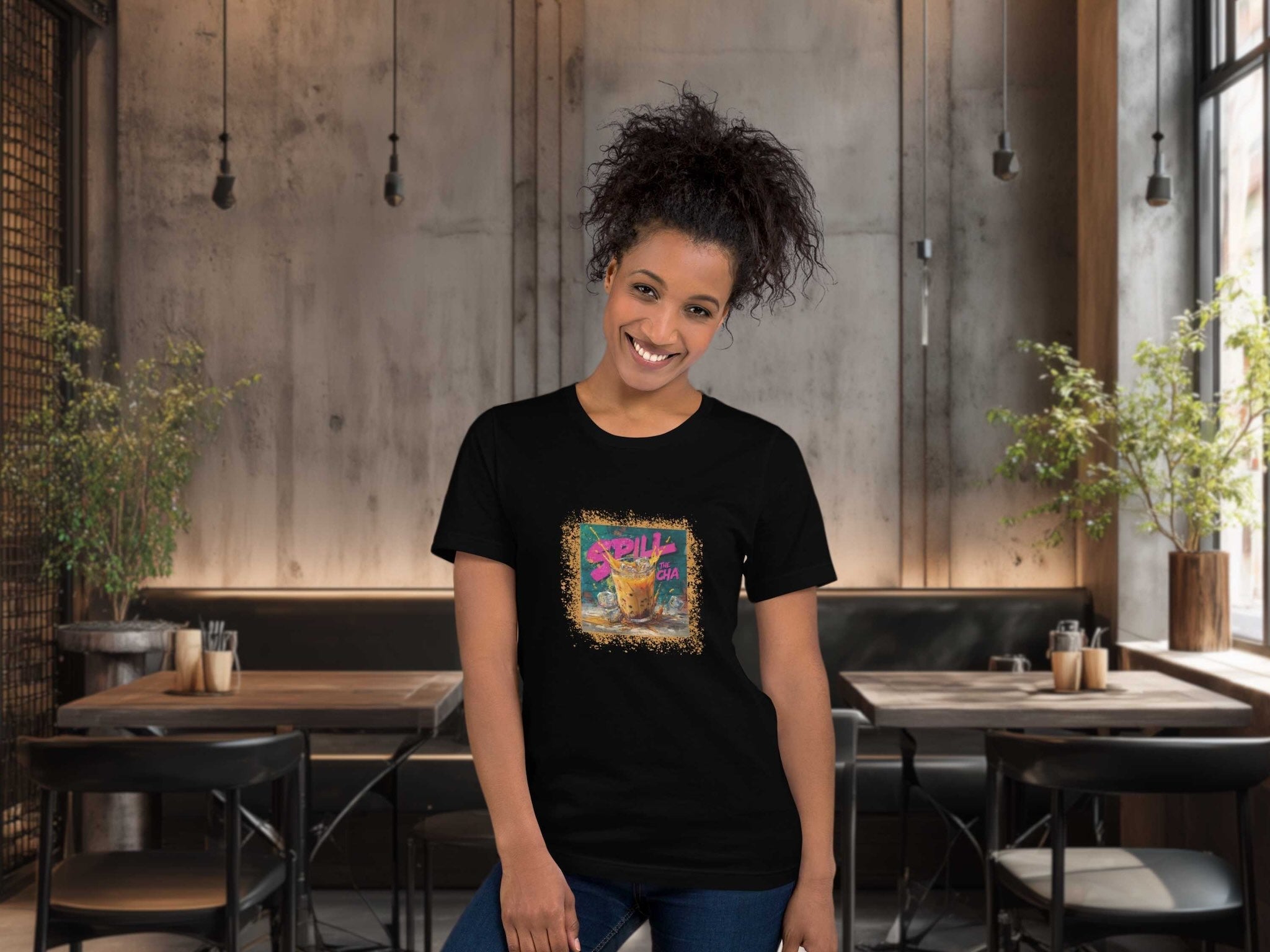 Woman wearing a black t-shirt with a colorful graphic design of thai milk tea graffiti style in a restaurant setting