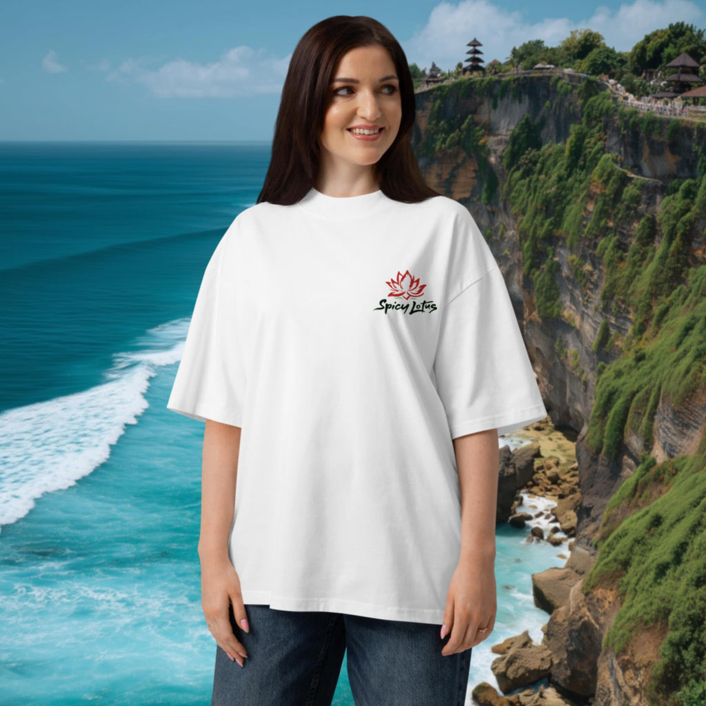 Woman wearing a white t-shirt with a Spicy Lotus chest logo in front of a scenic ocean and cliff backdrop