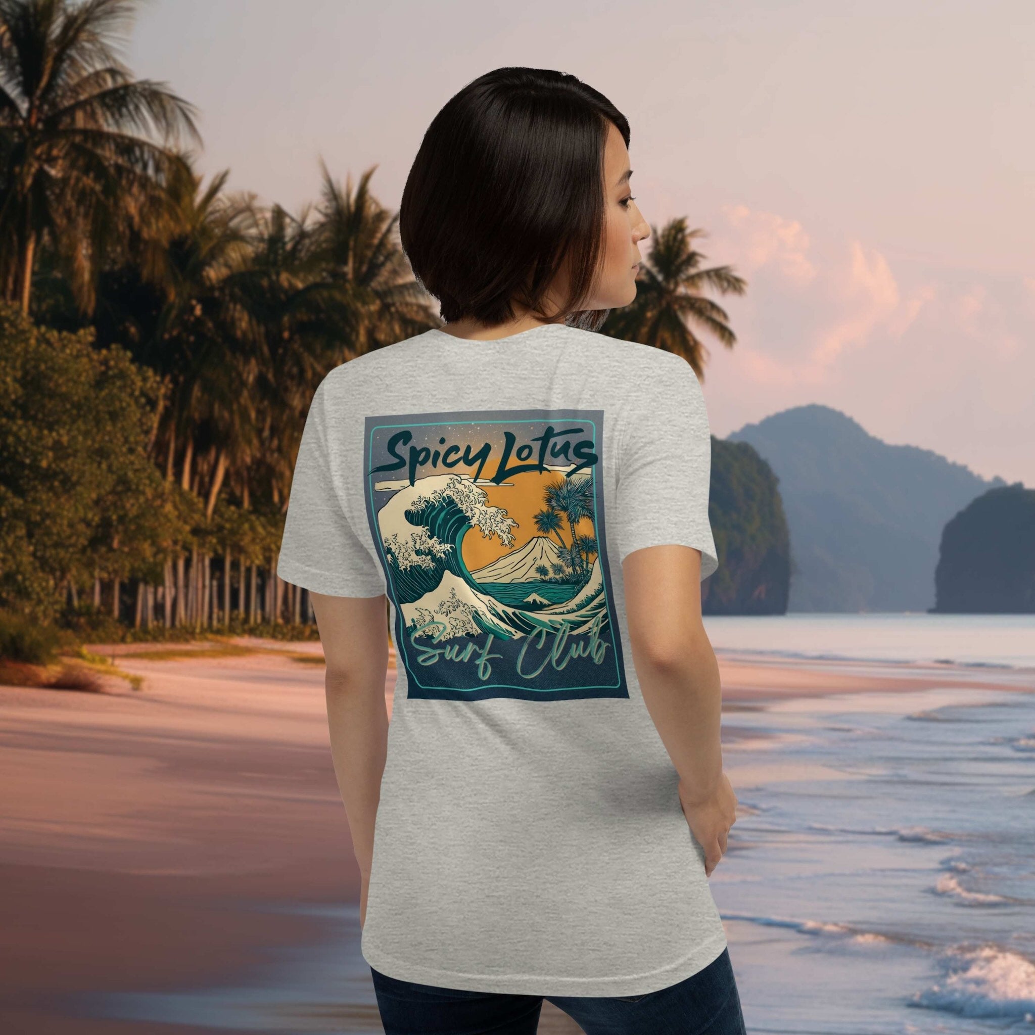 Person wearing a t-shirt with 'Spicy Lotus Surf Club' design on a beach.