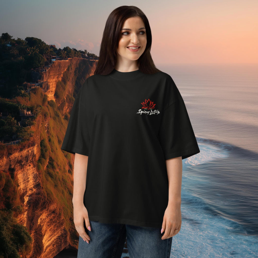 Woman wearing a black high-neck ribbed collar and dropped shoulders oversized tee  with a logo in front of a scenic background in Uluwatu, Bali.