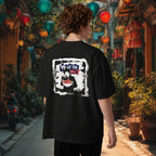 Person wearing a black t-shirt with a grafftiti graphic design of vietnamese soup pho in an outdoor setting with colorful lanterns, in Hoin An, Vietnam