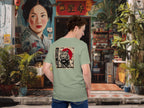 Person wearing a green t-shirt with a tiger graphic design in an urban setting with colorful murals and plants.