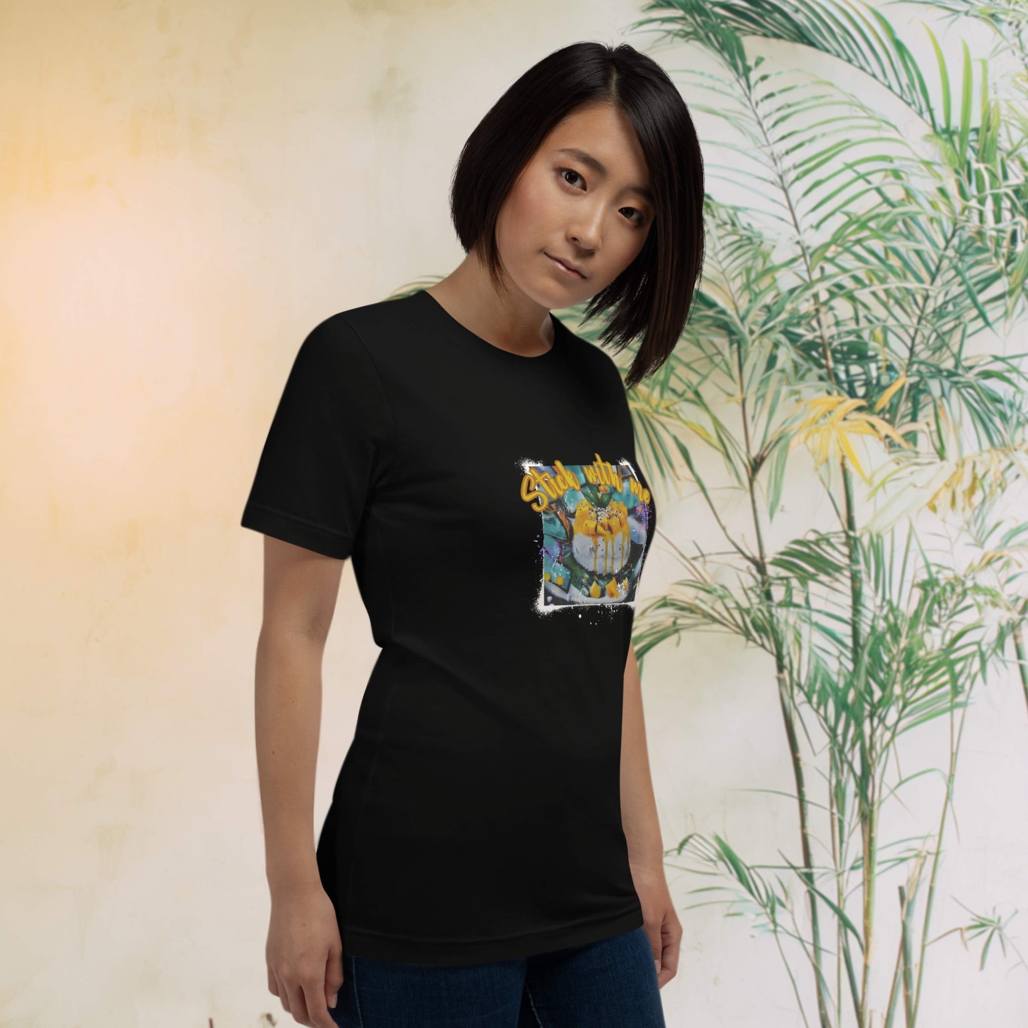 Person wearing a black t-shirt with a graphic design in front of a leafy background