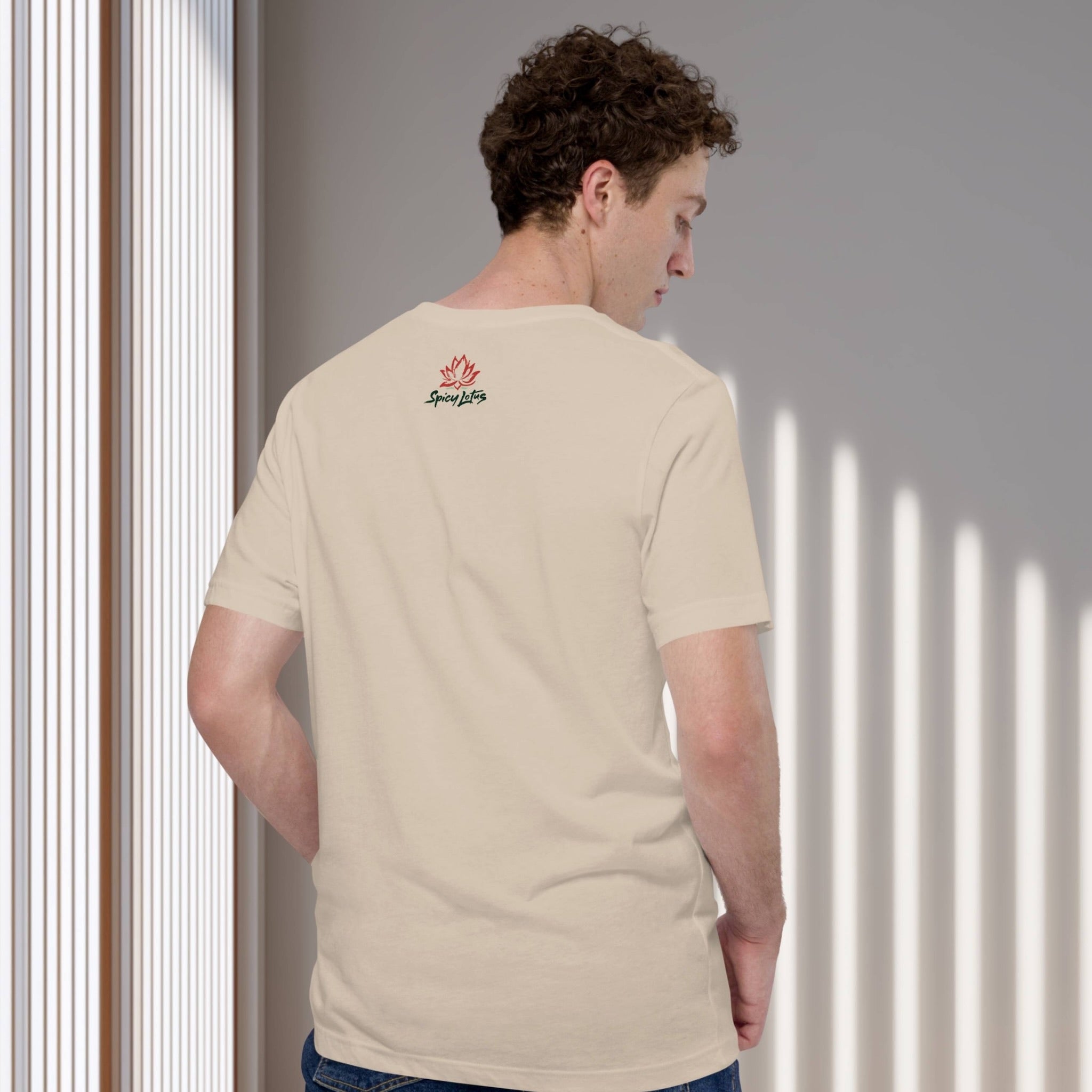 Man wearing a beige t-shirt with a Spicy Lotus logo on the back, standing against a neutral wall.