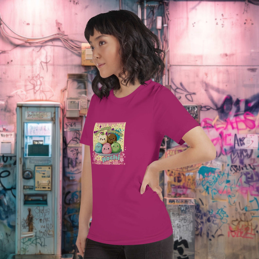 Person wearing a pink t-shirt with a colorful graphic design of mochis and the text 'too much is never mochi' in front of a graffiti-covered wall.