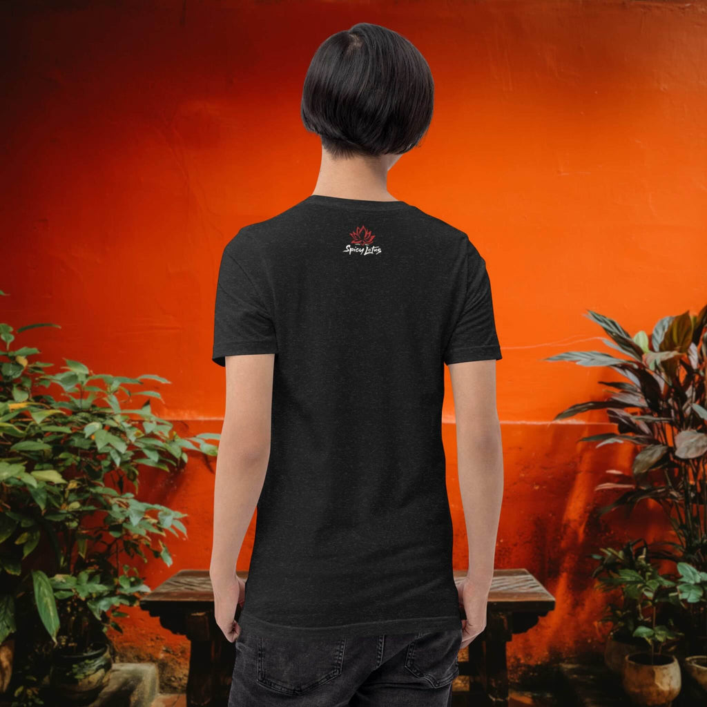Person wearing a black t-shirt with a logo on the back, standing in front of an orange wall with plants.