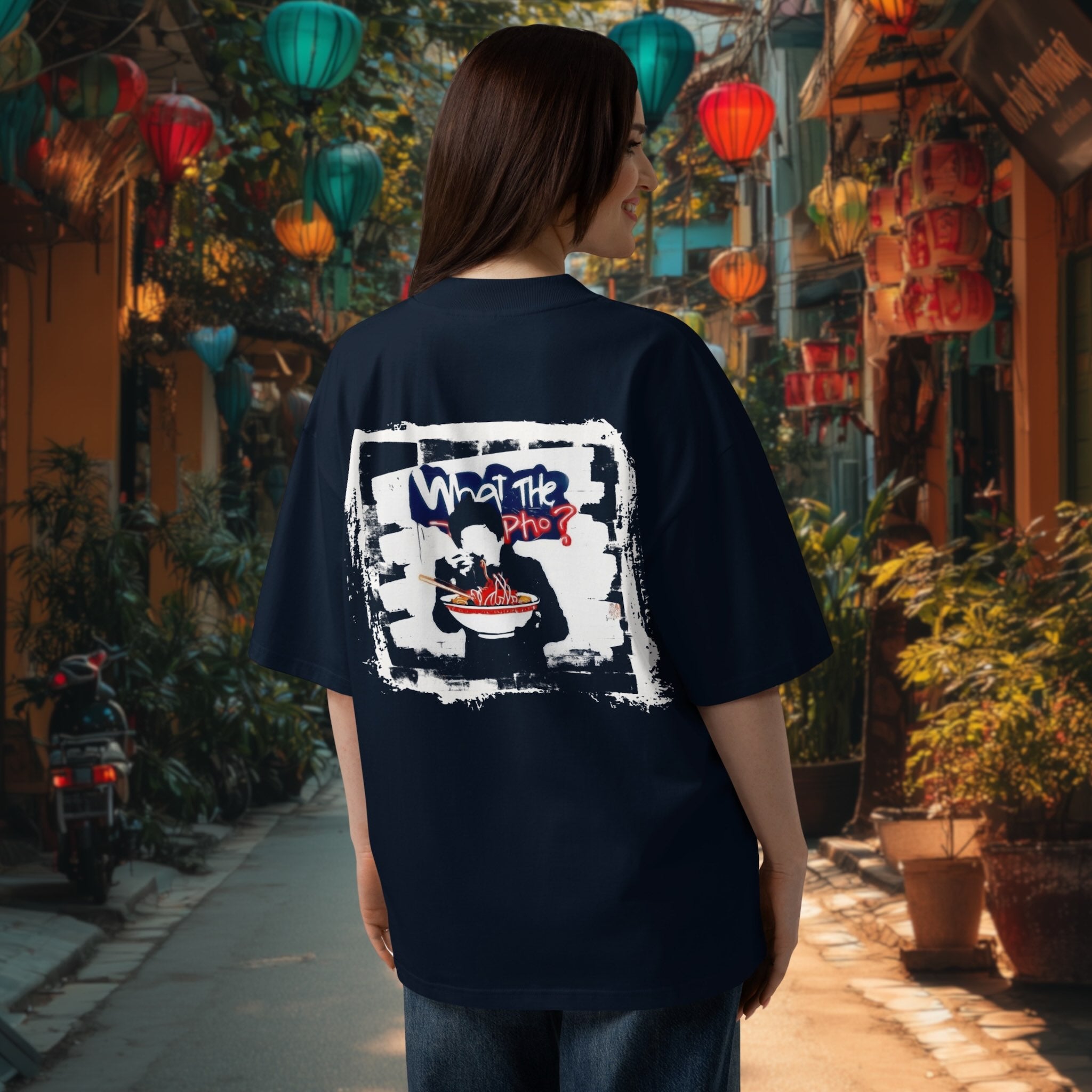 Woman wearing a bnavy blue oversized organic t-shirt with a graphic design of vietnamese oho in graffiti banky style in an outdoor setting with colorful lanterns.