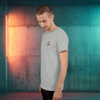 Man wearing a gray t-shirt with a logo against a colorful wall.