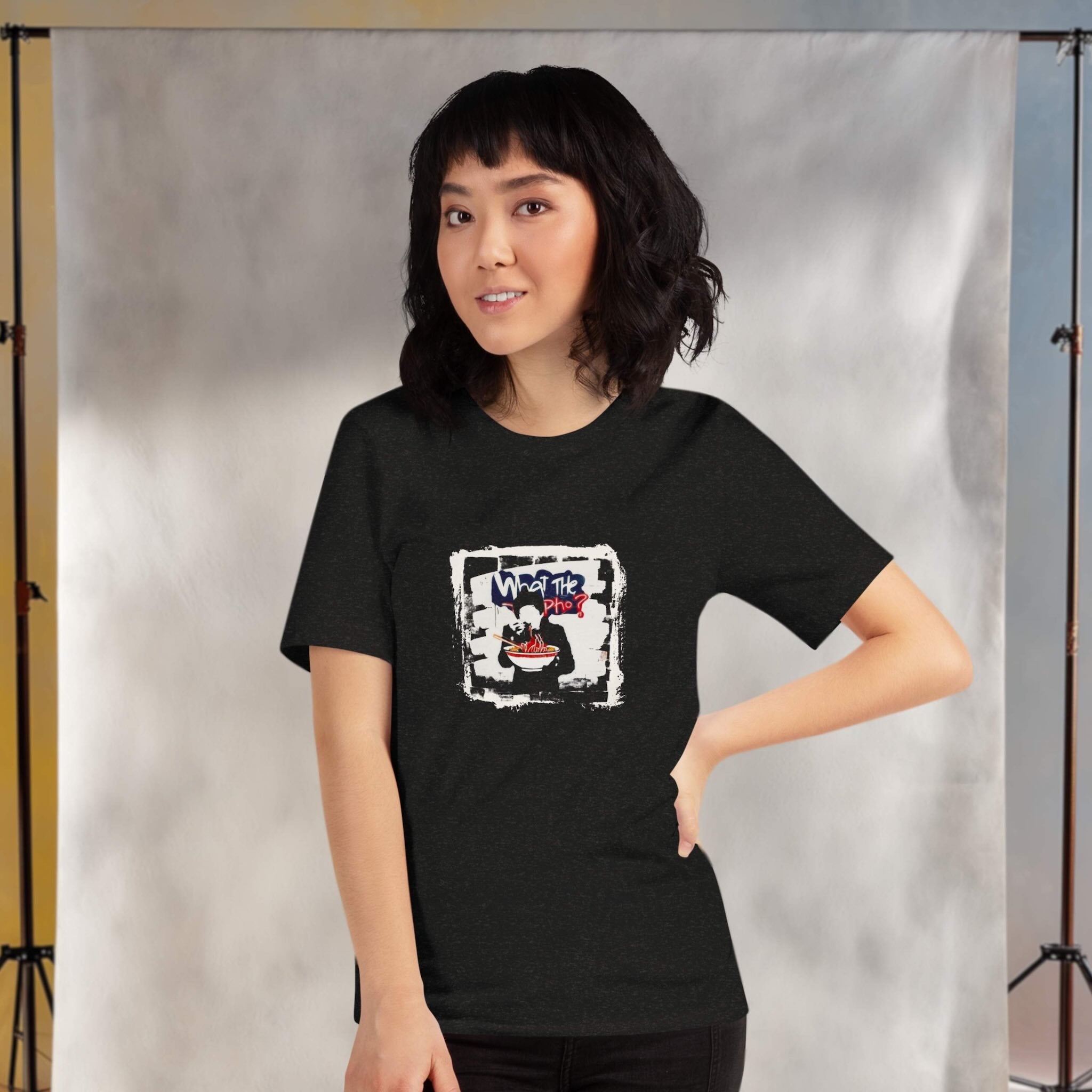 Person wearing a black t-shirt with a graphic design of 'what the pho?' against a neutral background